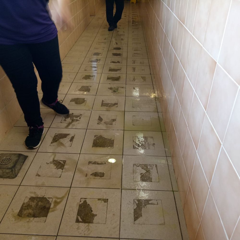 The same corridor before cleaning, with heavy stains on the tiles