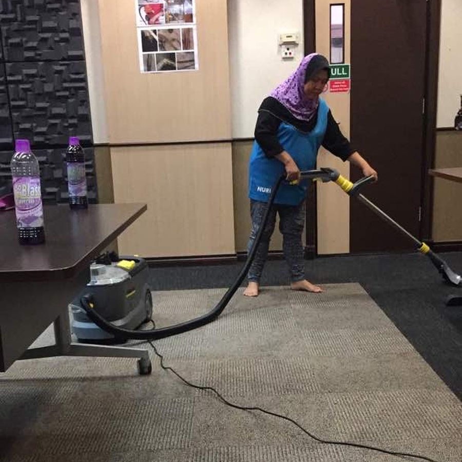 SHYT cleaner vacuuming carpet in a shoe-free meeting room