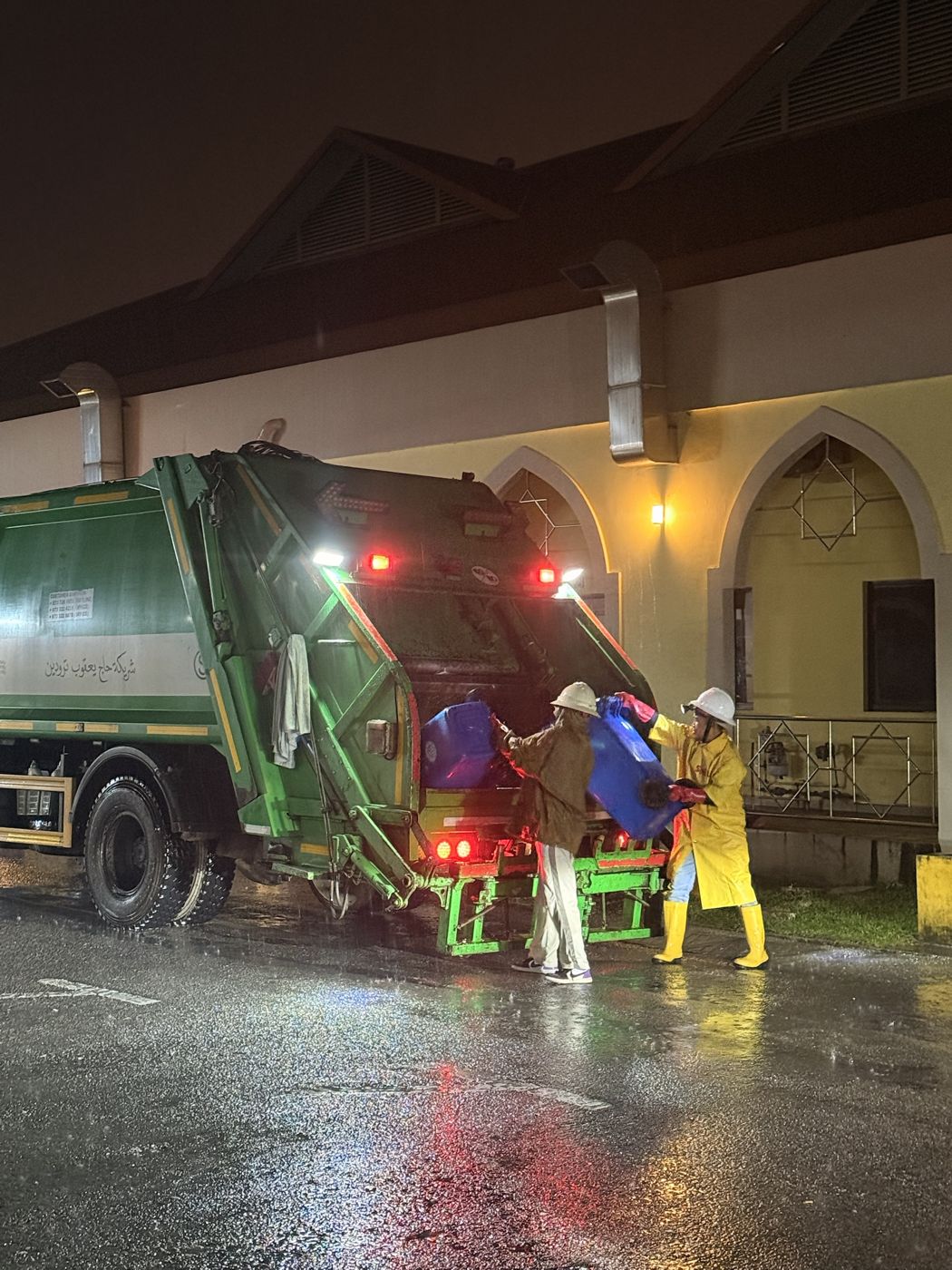 SHYT crew loading bins into a compactor truck at night